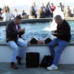 a group of people sitting next to a body of water